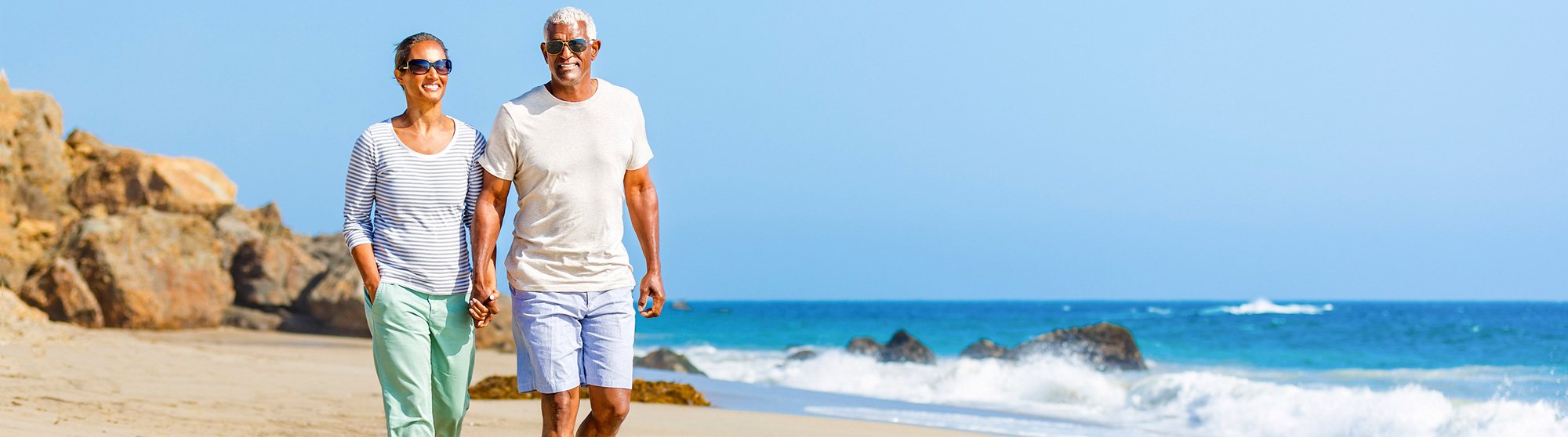 couple holding hands and walking on the beach