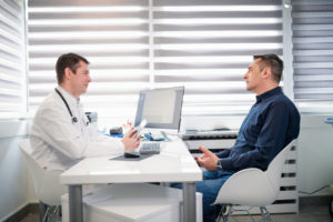 A man sitting down with his doctor to discuss his erectile dysfunction issues that he's dealing with.
