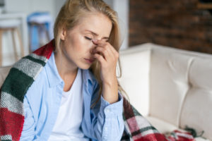 A woman holding her face as she suffers from chronic pain stemming from her head.