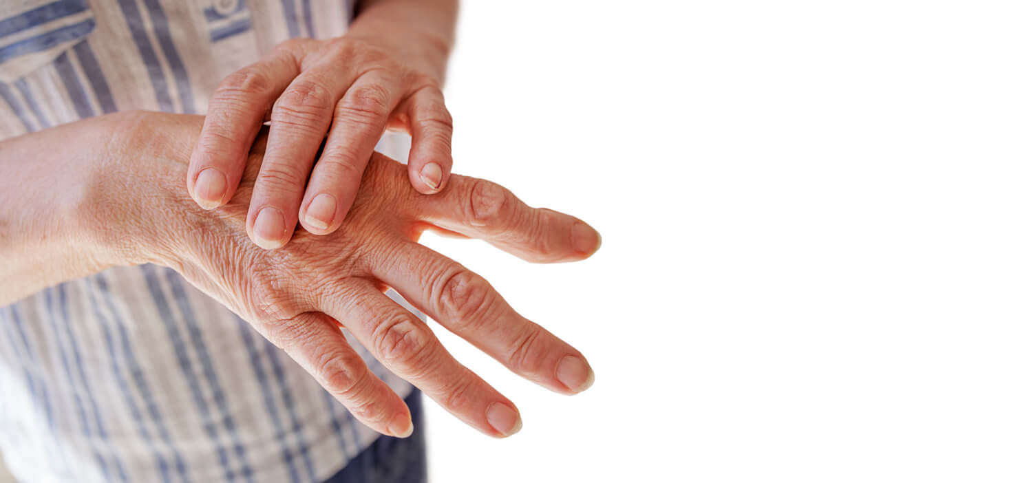 A close-up image of an elderly woman's hand with arthritis, massaging the painful area.