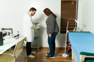 A family medicine doctor is checking the weight of a patient.